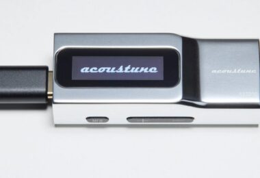 Dongle DAC USB-C Acoustune AS2200 en aluminium argent vu de profil, écran OLED affichant le logo acoustune, câble USB-C branché