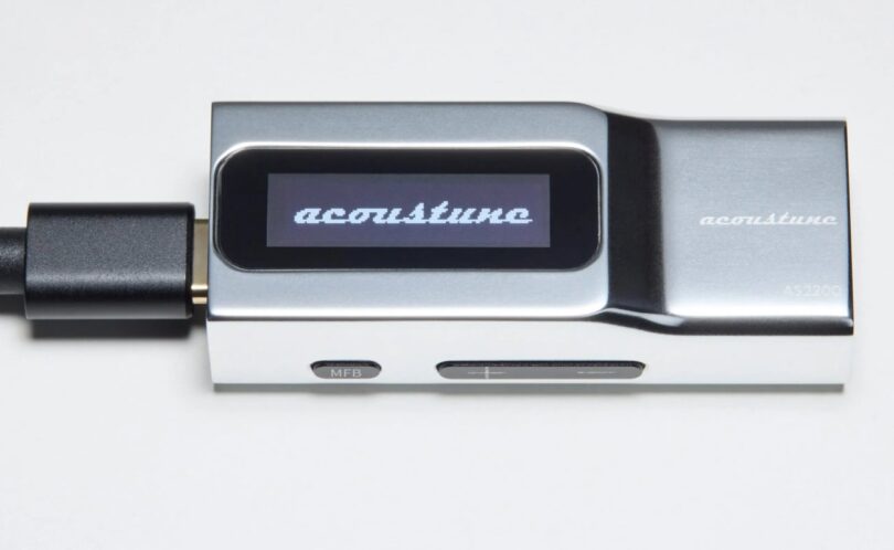 Dongle DAC USB-C Acoustune AS2200 en aluminium argent vu de profil, écran OLED affichant le logo acoustune, câble USB-C branché