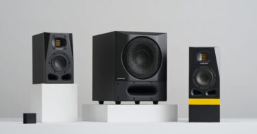 Caisson de basses actif ADAM Audio Sub8 PRO noir avec grille métallique et évent frontal moucheté, posé entre deux moniteurs de studio ADAM série A sur fond gris clair