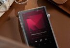 Baladeur audiophile Astell&Kern PD5 posé sur du cuir dans son étui TPU transparent, écran tactile 4,1 pouces en lecture DSD, molette de volume crantée et écouteurs intra-auriculaires