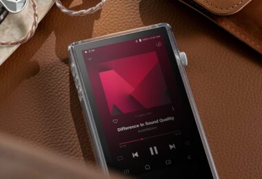 Baladeur audiophile Astell&Kern PD5 posé sur du cuir dans son étui TPU transparent, écran tactile 4,1 pouces en lecture DSD, molette de volume crantée et écouteurs intra-auriculaires