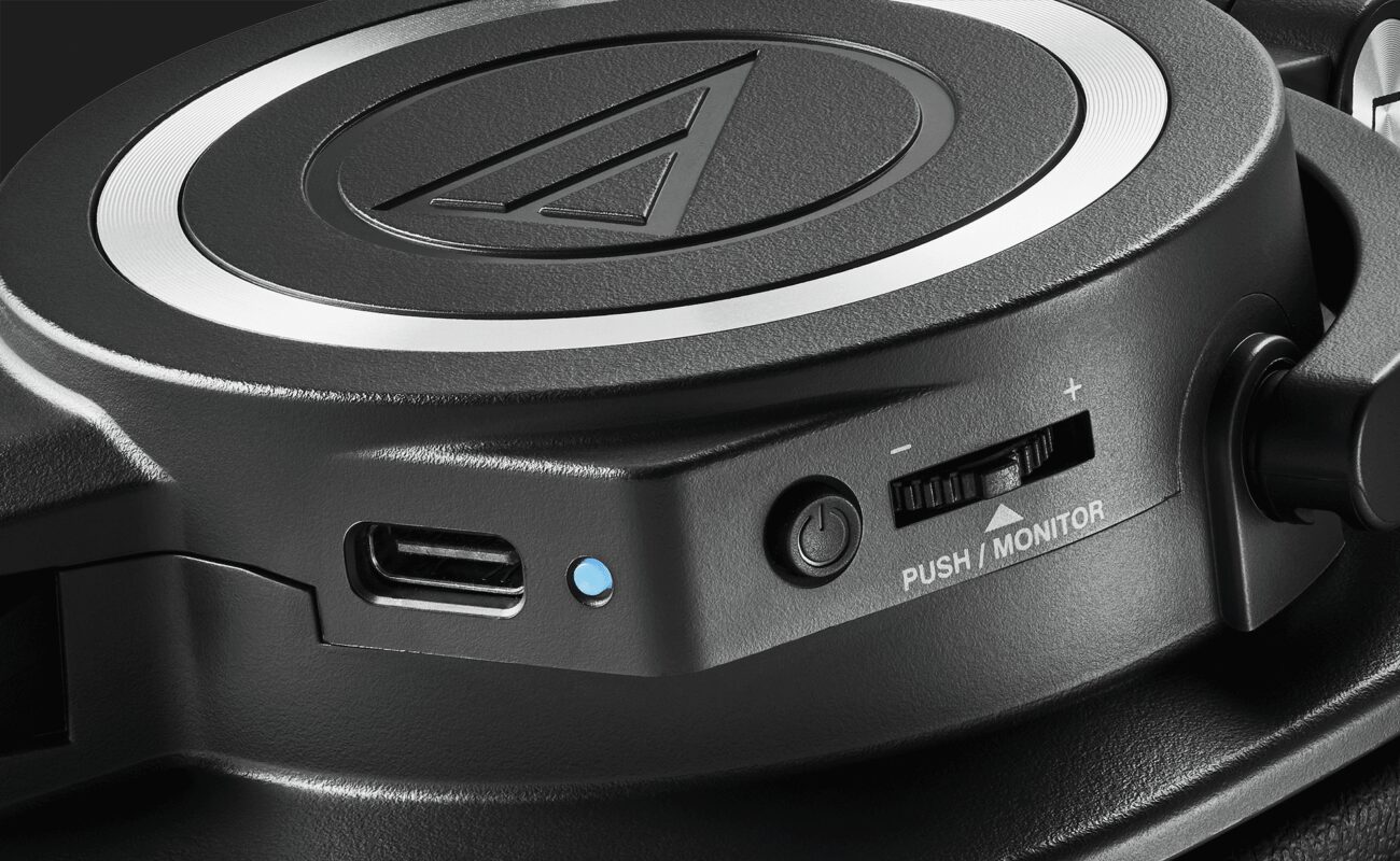 Gros plan sur l oreillette de l ATH-M50xSTS-WL : prise USB-C de charge, voyant, bouton et molette de retour micro