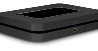 Streamer réseau Bluesound NODE noir vu de trois quarts sur fond blanc, avec surface tactile sur le dessus, logo Bluesound et prise casque en façade