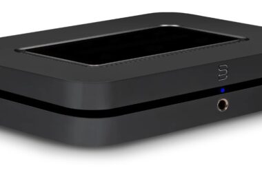 Streamer réseau Bluesound NODE noir vu de trois quarts sur fond blanc, avec surface tactile sur le dessus, logo Bluesound et prise casque en façade