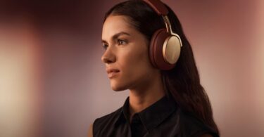 Femme écoutant de la musique avec un casque sans fil Bowers & Wilkins bordeaux et or, visuel officiel de l application Bowers & Wilkins Music