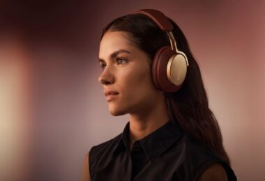 Femme écoutant de la musique avec un casque sans fil Bowers & Wilkins bordeaux et or, visuel officiel de l application Bowers & Wilkins Music