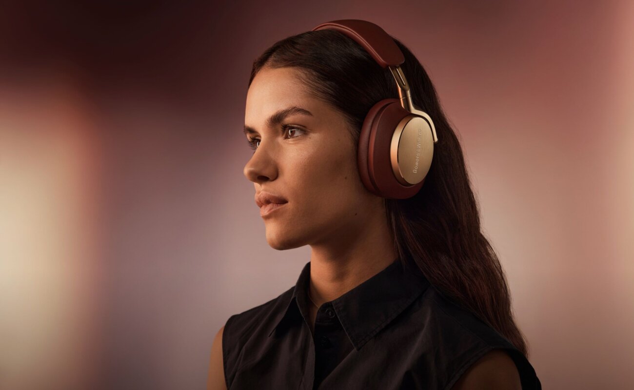 Femme écoutant de la musique avec un casque sans fil Bowers & Wilkins bordeaux et or, visuel officiel de l application Bowers & Wilkins Music