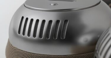 Oreillette du casque Bluetooth écoute TH2 en finition nickel avec coque métallique ajourée de fentes d'aération et coussinet en tissu beige