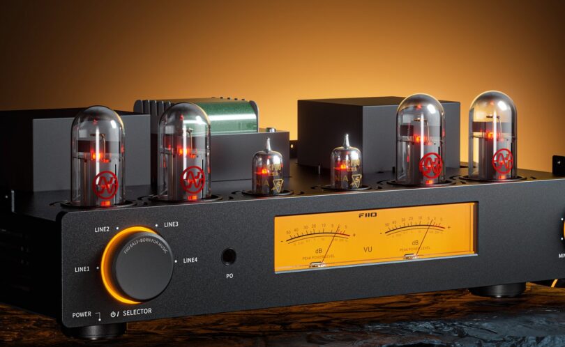 Amplificateur à tubes FiiO EA13 en finition noire, quatre lampes de puissance JJ EL34 et deux Sylvania NOS PCF80 allumées, transformateurs, sélecteur LINE1 à LINE4 rétroéclairé, prise casque et double VU-mètre ambré