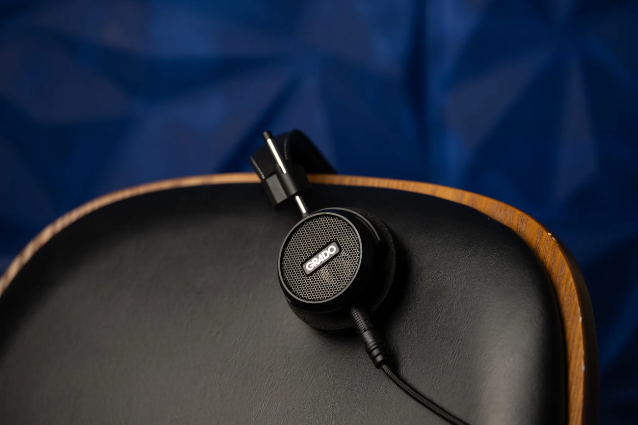 Casque Grado Signature S150 posé sur l'accoudoir d'un fauteuil en cuir noir et bois, coque à grille et câble noir