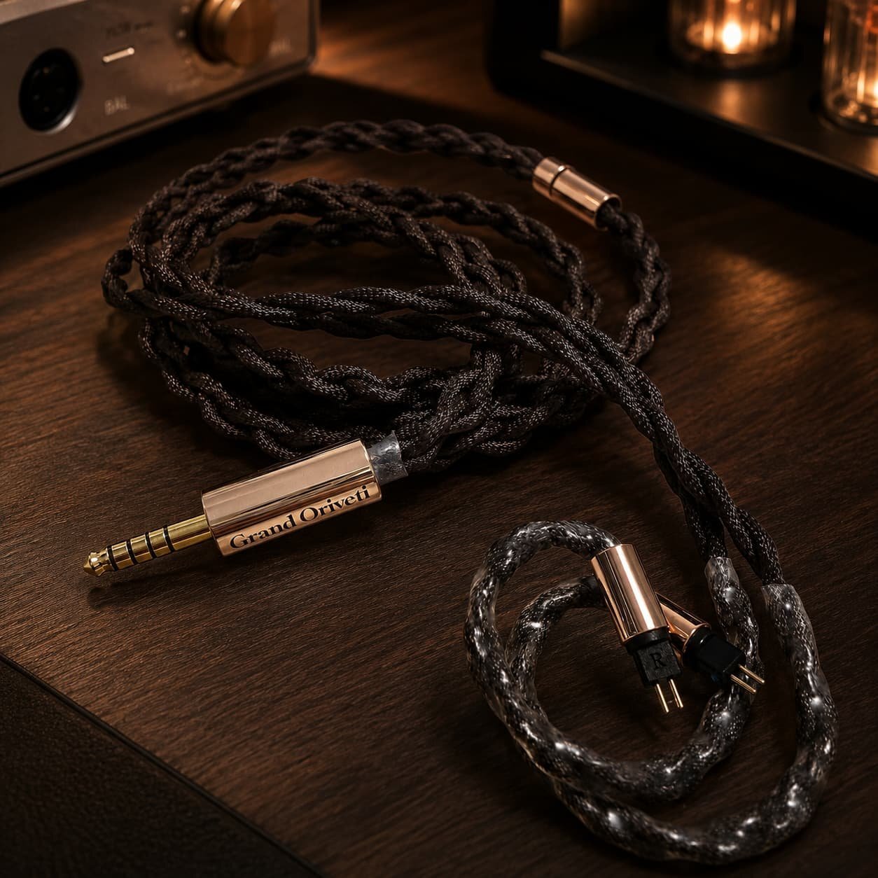 Câble Grand Affinity tressé en cuivre OCC et OCC argenté, fiche symétrique 4,4 mm dorée et connecteurs 2 broches 0,78 mm, posé sur une table en bois