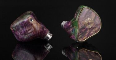 Paire d'intra-auriculaires Grand Oriveti Eminency à coque en bois stabilisé et résine aux tons violets et verts, façade à incrustation dorée, sur fond noir réfléchissant
