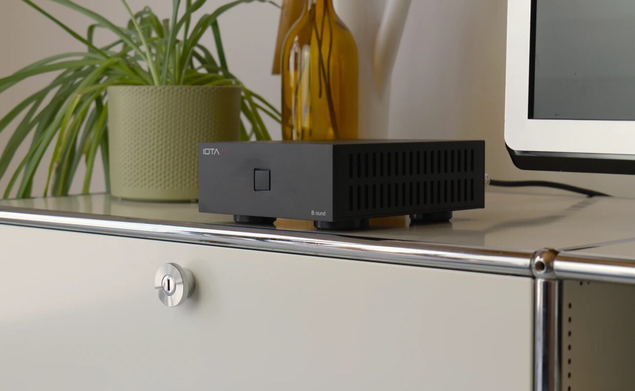 Ampli de puissance IOTAVX B:ound noir posé sur un meuble blanc, à côté d'une plante