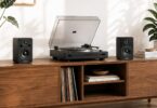 Paire d'enceintes actives Marmitek Soundex S300 noires, tweeter à dôme et woofer de 3 pouces, posées de part et d'autre d'une platine vinyle sur un meuble en bois clair