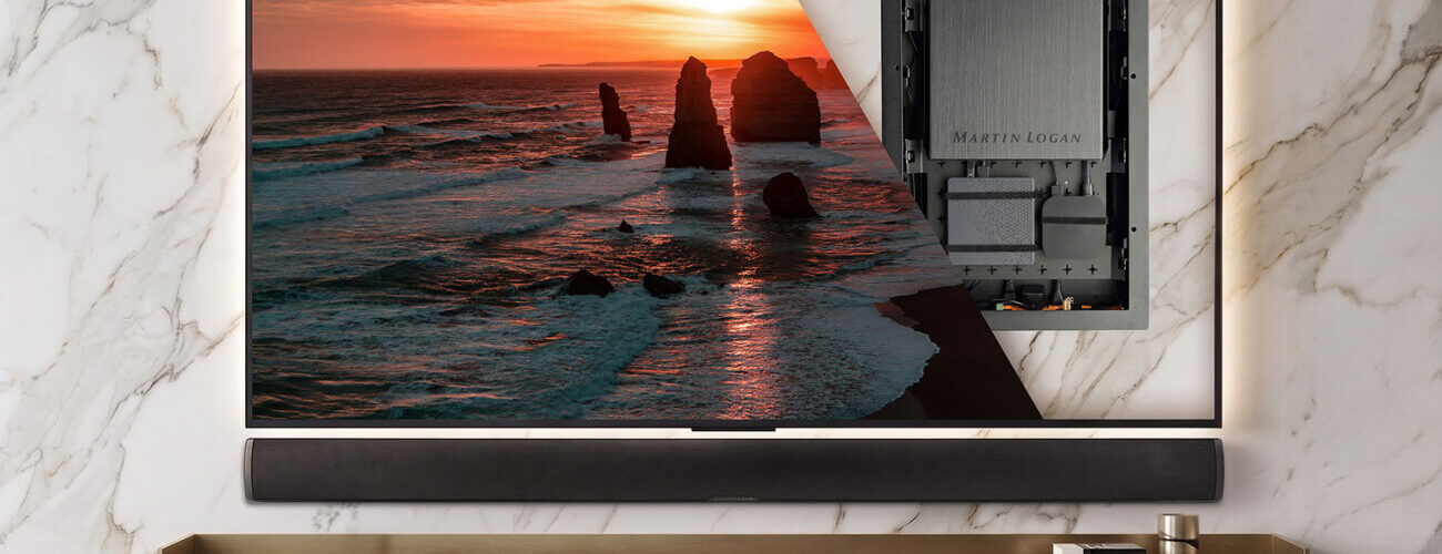 MartinLogan USR51 fixé au dos d'un téléviseur mural, révélé par une vue en transparence, au-dessus d'une barre de son passive et d'un meuble TV en bois