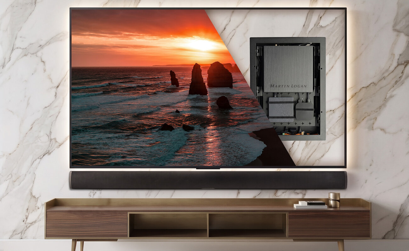 MartinLogan USR51 fixé au dos d'un téléviseur mural, révélé par une vue en transparence, au-dessus d'une barre de son passive et d'un meuble TV en bois