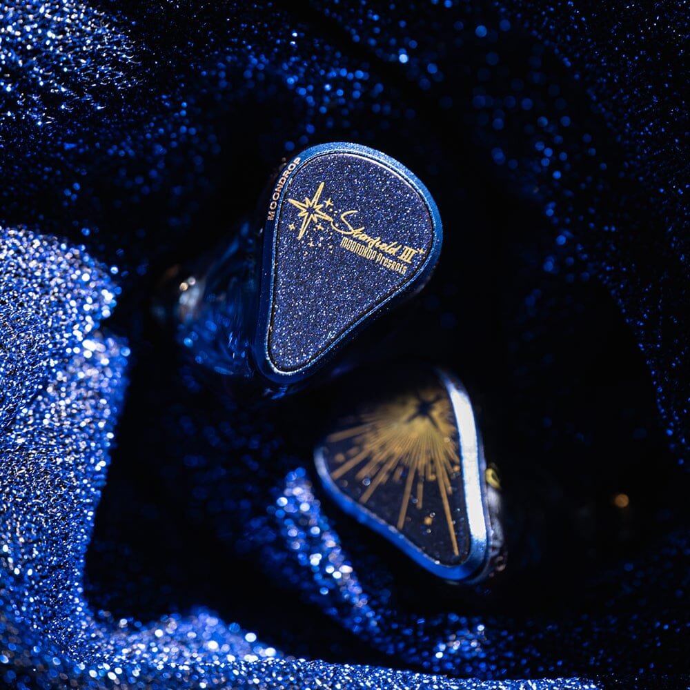 Paire d'intra-auriculaires Moondrop Starfield 3 sur fond bleu scintillant, plaques pailletées avec logo Starfield et motif d'étoile doré