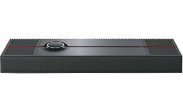 Système tout-en-un Naim Mu-so Utopia vu de trois quarts dessus, coffret noir d'un mètre de large à grilles rainurées, liseré rouge et molette de commande rétroéclairée