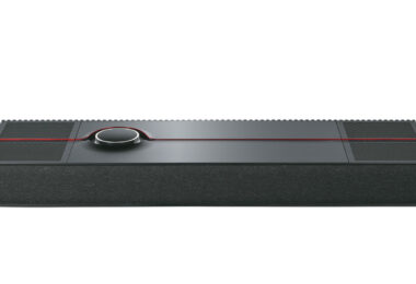 Système tout-en-un Naim Mu-so Utopia vu de trois quarts dessus, coffret noir d'un mètre de large à grilles rainurées, liseré rouge et molette de commande rétroéclairée