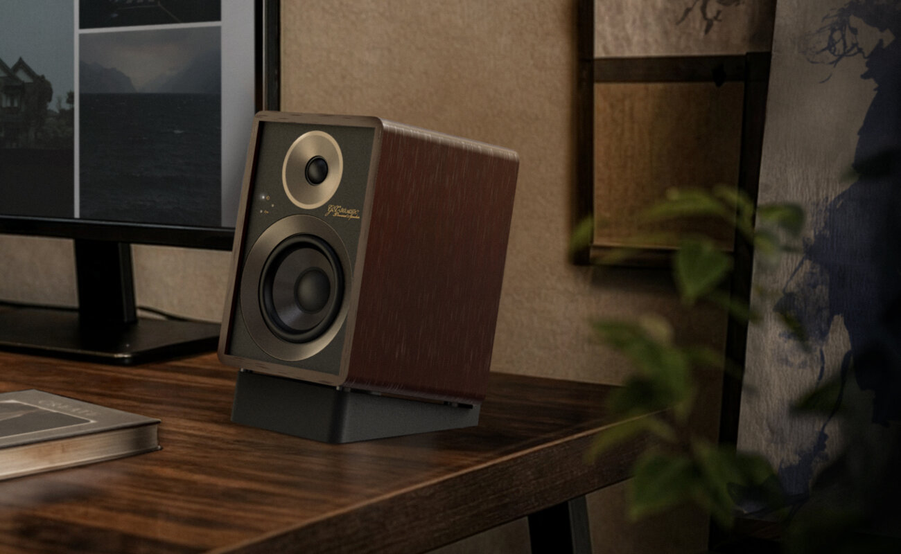 Enceinte active Onkyo GX-30ARC édition 80 ans en finition noyer Bordeaux, façade noire texturée et cerclages gris foncé, posée sur son pied incliné noir au coin d'un bureau en bois