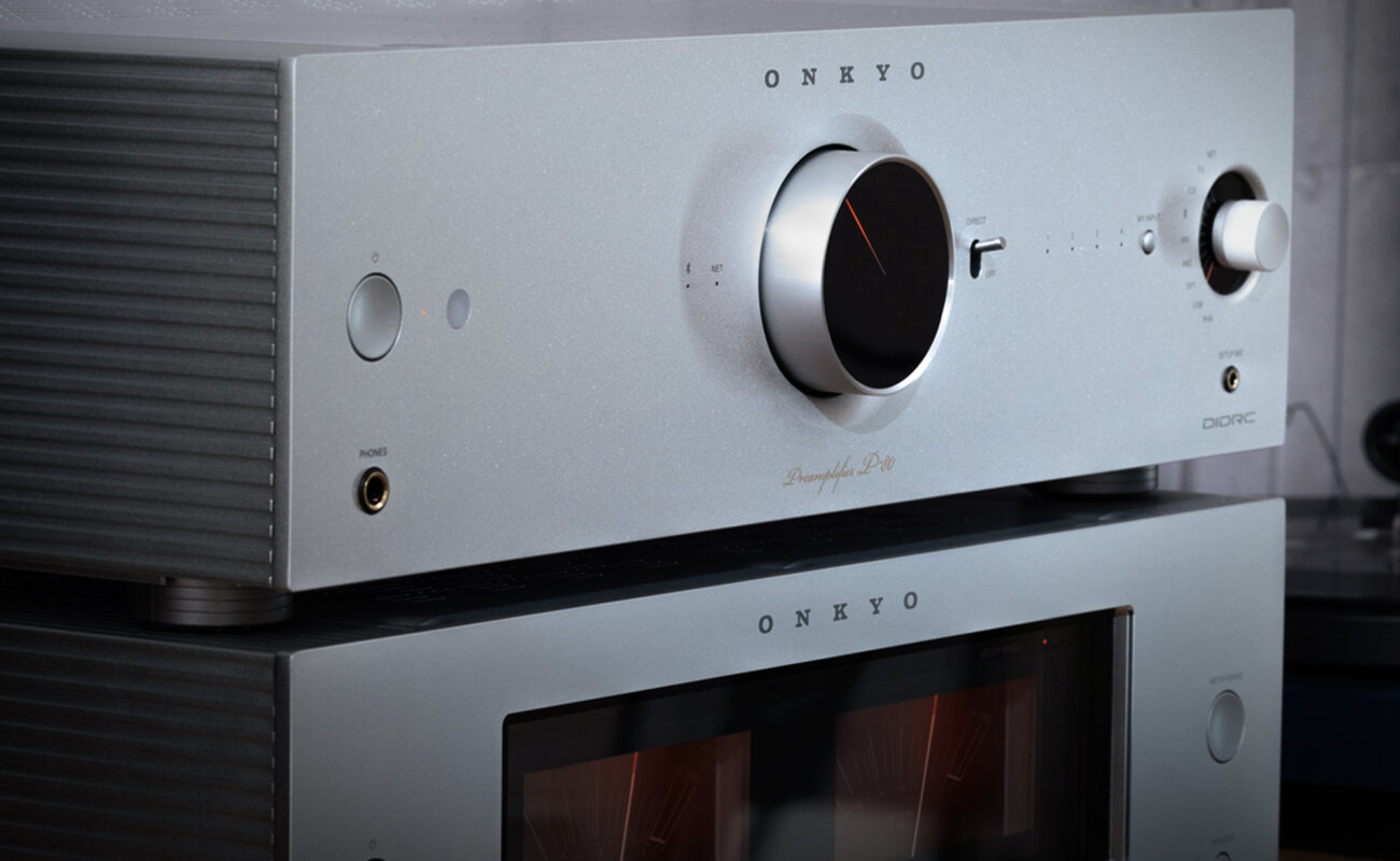 Préampli réseau Onkyo Icon P-80 argent posé sur l'ampli de puissance M-80 et ses deux vumètres, vus de trois quarts dans un salon à côté d'une platine vinyle