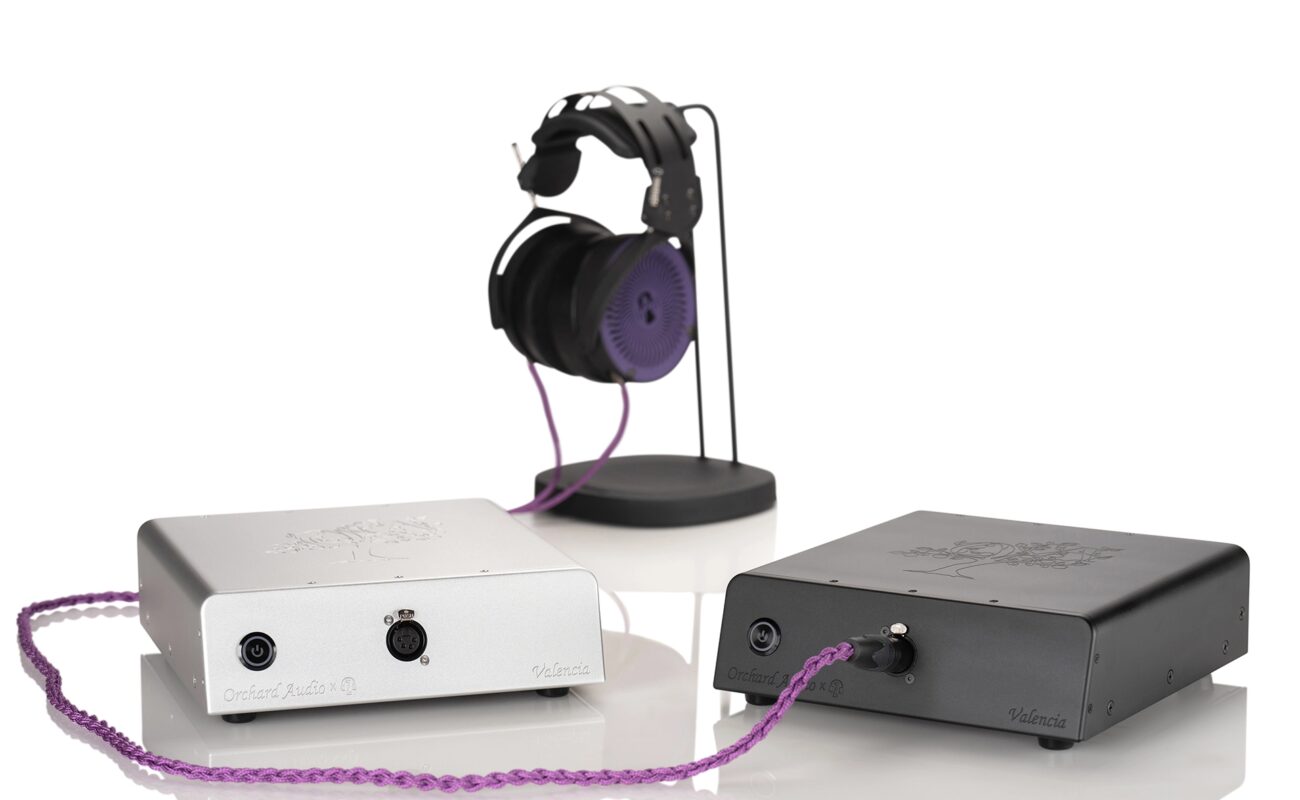 Deux amplis de puissance pour casque Orchard Audio Valencia MG en finitions argent et noir, sortie XLR 4 broches en façade, câble violet relié à un casque posé sur son support