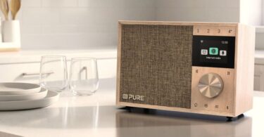 Radio Pure Evoke One en bois de bouleau posée sur un plan de travail de cuisine, grille en tissu, écran couleur affichant le menu radio Internet, molette en métal et touches de présélection