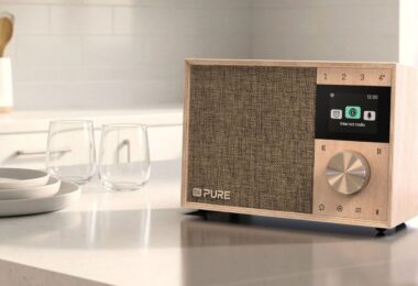 Radio Pure Evoke One en bois de bouleau posée sur un plan de travail de cuisine, grille en tissu, écran couleur affichant le menu radio Internet, molette en métal et touches de présélection
