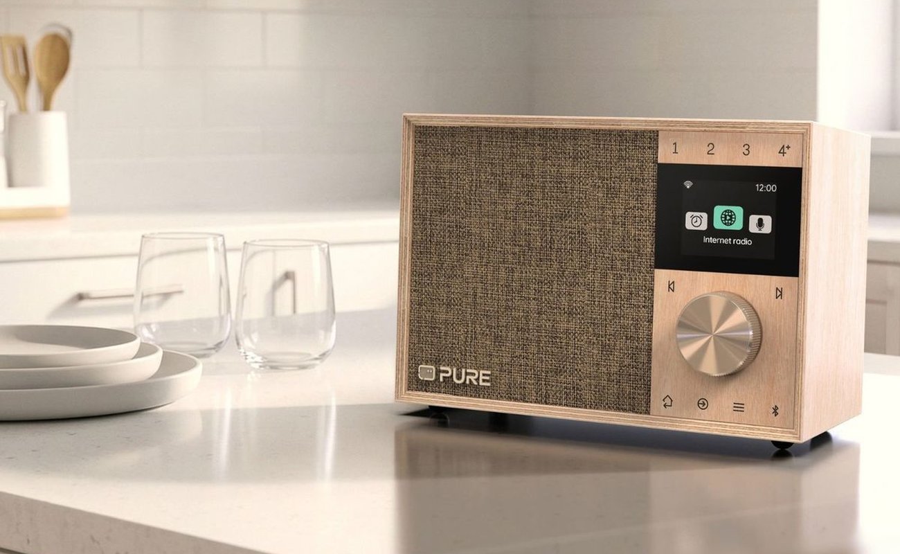 Radio Pure Evoke One en bois de bouleau posée sur un plan de travail de cuisine, grille en tissu, écran couleur affichant le menu radio Internet, molette en métal et touches de présélection