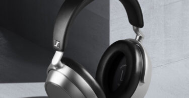 Casque sans fil Sennheiser HDB 630 en finition Lunar Silver vu de trois quarts, coques argentées au rendu mat, arceau noir en similicuir japonais IDEATEX et coussinets circum-auriculaires noirs, posé contre un mur de béton gris