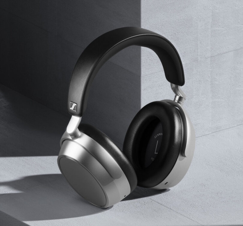 Casque sans fil Sennheiser HDB 630 en finition Lunar Silver vu de trois quarts, coques argentées au rendu mat, arceau noir en similicuir japonais IDEATEX et coussinets circum-auriculaires noirs, posé contre un mur de béton gris