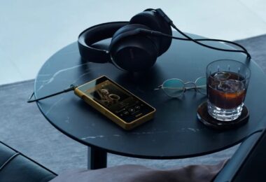 Baladeur Sony Walkman NW-WM1ZM3 à châssis en cuivre sans oxygène plaqué or posé sur une table avec un casque filaire, écran 5,5 pouces et lecteur de musique affiché