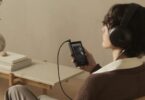 Auditeur assis dans un fauteuil écoutant de la musique au casque Sony sur le baladeur Walkman NW-ZX900 noir à écran 5 pouces Full HD relié par câble