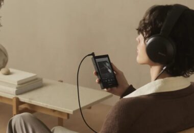 Auditeur assis dans un fauteuil écoutant de la musique au casque Sony sur le baladeur Walkman NW-ZX900 noir à écran 5 pouces Full HD relié par câble