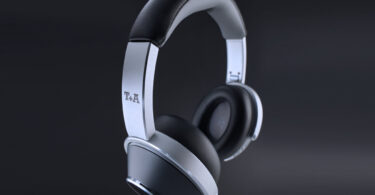 Casque sans fil T+A Solitaire T Pro en finition Nightflight, arceau aluminium brossé et coques noires à anneau argenté, logo T+A sur la branche, sur fond sombre