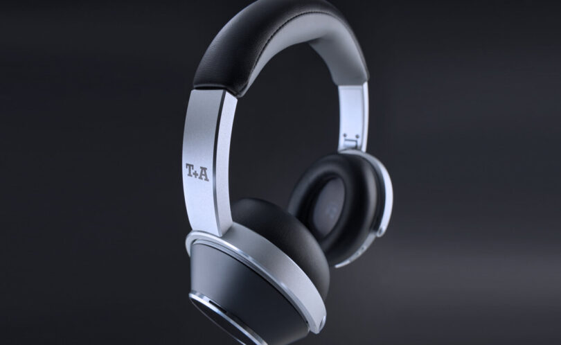 Casque sans fil T+A Solitaire T Pro en finition Nightflight, arceau aluminium brossé et coques noires à anneau argenté, logo T+A sur la branche, sur fond sombre