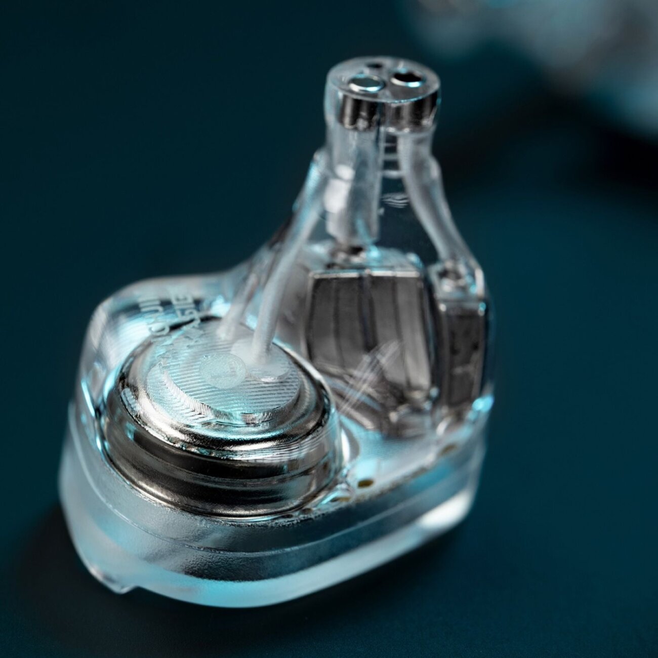 Gros plan sur une coque transparente de Tanchjim KASIER montrant le transducteur dynamique DMT 5 de 10 mm, les blocs d'armatures et les conduits acoustiques menant à la canule