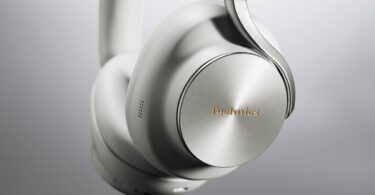 Casque sans fil Technics EAH-A1000 coloris Platinum Greige, gros plan sur l'écouteur avec sa coque en métal à finition circulaire, le logo Technics doré et l'arceau Flow Arm