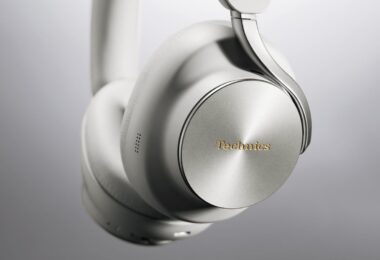 Casque sans fil Technics EAH-A1000 coloris Platinum Greige, gros plan sur l'écouteur avec sa coque en métal à finition circulaire, le logo Technics doré et l'arceau Flow Arm