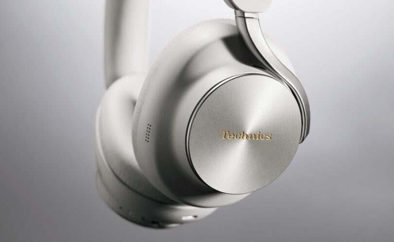 Casque sans fil Technics EAH-A1000 coloris Platinum Greige, gros plan sur l'écouteur avec sa coque en métal à finition circulaire, le logo Technics doré et l'arceau Flow Arm