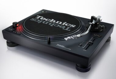 Platine DJ Technics SL-1210MKX noire vue de trois quarts avec plateau, feutrine Technics, bras en S argent poli, curseur de pitch et nouveaux pieds isolants