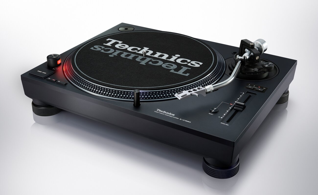 Platine DJ Technics SL-1210MKX noire vue de trois quarts avec plateau, feutrine Technics, bras en S argent poli, curseur de pitch et nouveaux pieds isolants
