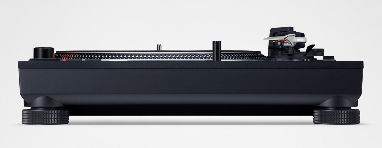 Technics SL-1210MKX vue de profil montrant le châssis alourdi de 169 mm de haut, le bras argent et les nouveaux pieds isolants anti-larsen