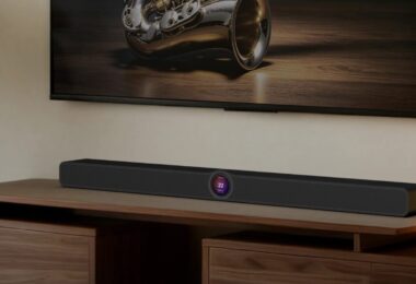 Barre de son WiiM Bar noire posée sur un meuble TV en noyer sous un téléviseur, avec son écran tactile rond de 2,1 pouces au centre de la façade, dans un salon chaleureux