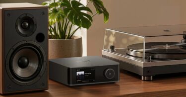 Streamer WiiM Ultra actuel à écran tactile posé entre une enceinte bibliothèque et une platine vinyle